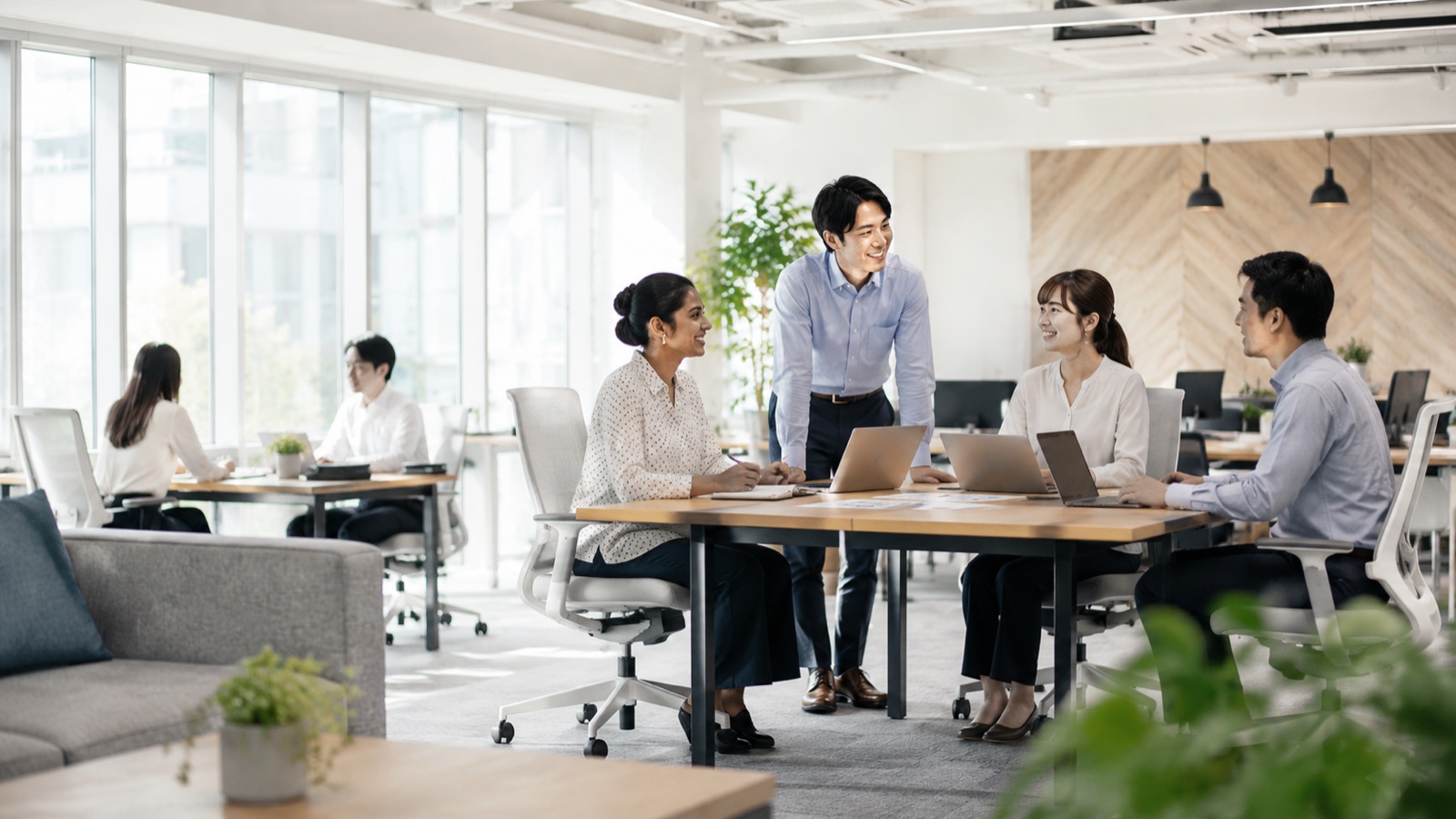 明るいオフィスで日本人社員と外国人社員が笑顔で打ち合わせをしている様子